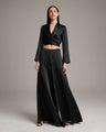 Woman wearing a black outfit with a long skirt and top on a plain background