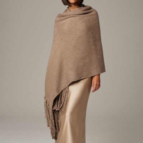Brown knitted shawl draped over a person on a plain background