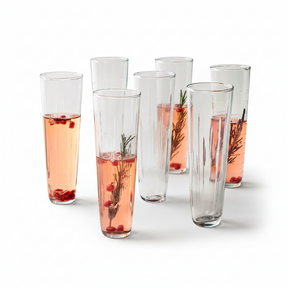 Set of six tall glasses with pink beverages and garnishes on a white background