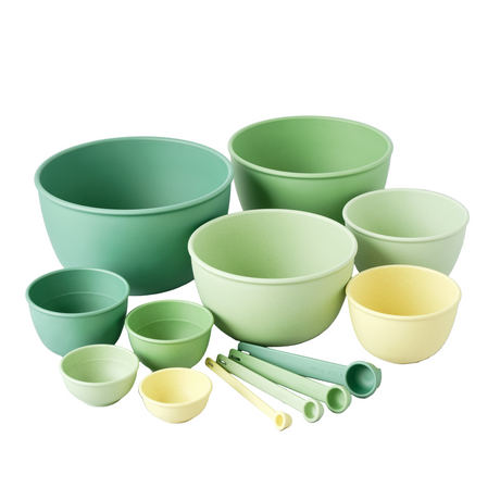 Set of green and yellow bowls and measuring cups on a light surface
