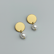 Gold earrings with pearls on a light gray background