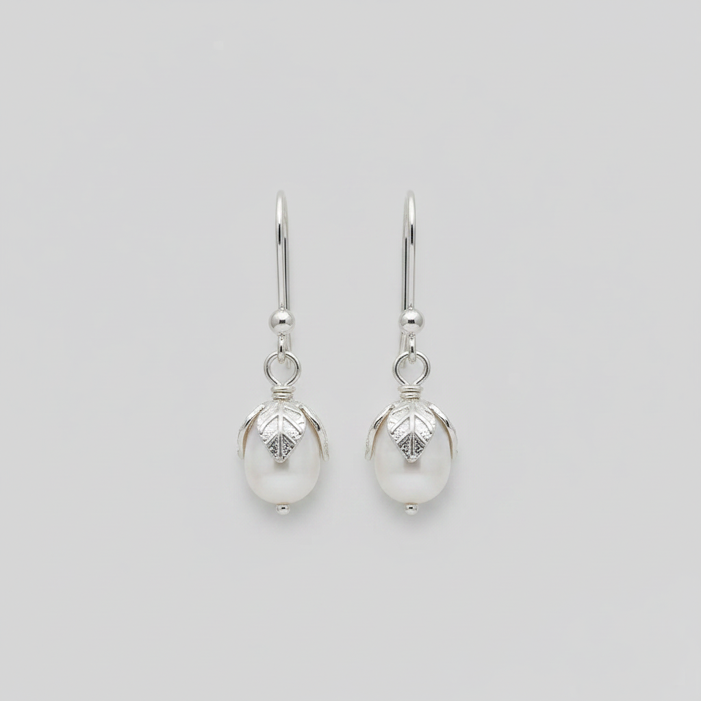 Pair of silver earrings with pearl-like beads on a light gray background