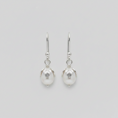 Pair of silver earrings with pearl-like beads on a light gray background