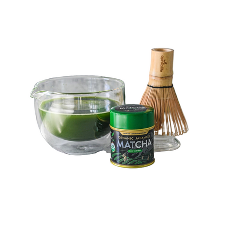 Matcha green tea set with glass bowl, matcha container, and whisk on a white background