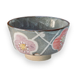 The Gray with Flowers Ceramic Matcha Bowl features a pink and red floral design on a gray background, set against black, ideal for enriching your tea accessories collection.