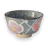 The Gray with Flowers Ceramic Matcha Bowl features a pink and red floral design on a gray background, set against black, ideal for enriching your tea accessories collection.