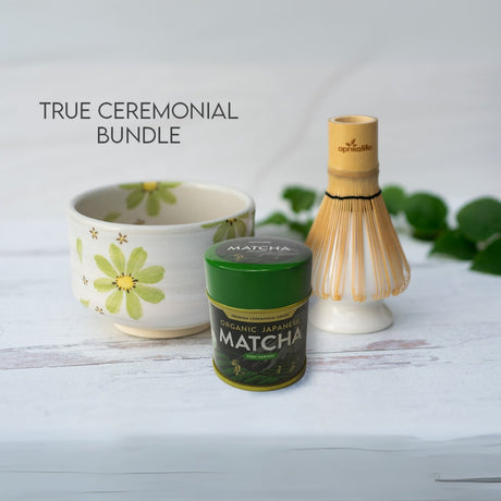 The "Green Flowers Matcha Set" includes a ceramic tea bowl, matcha container, and bamboo whisk on a white surface, highlighting the expertly handcrafted Minoyaki pottery techniques of the Green Flowers Ceramic Matcha Bowl.