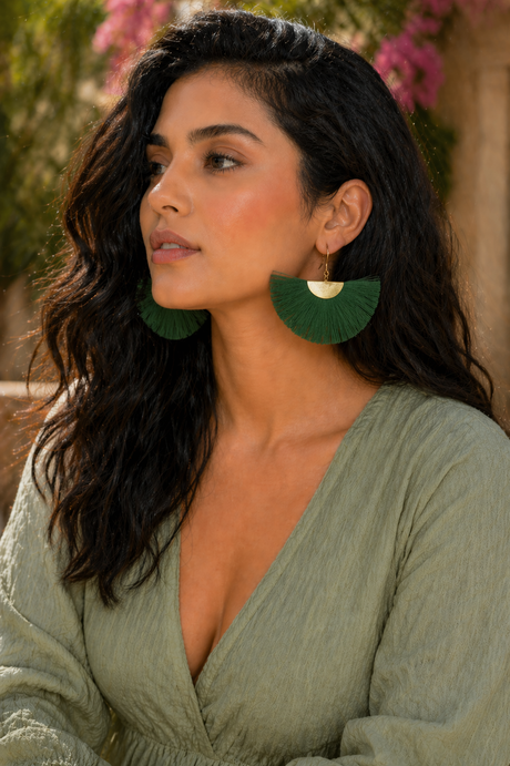 Woman wearing green earrings and a green dress with a blurred background