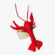Red lobster-shaped napkin ring with a small woven basket on a white background