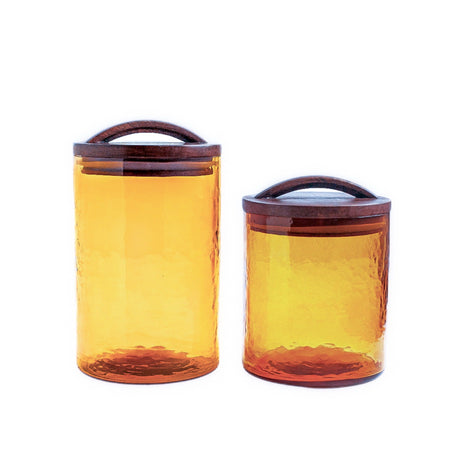 Two amber glass canisters with wooden lids on a white background