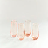Set of four pink glass tumblers on a light gray background
