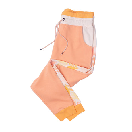 Peach-colored jogger pants with white drawstring and side stripes on a white background