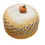Woven bread basket with a small pumpkin decoration on a white background