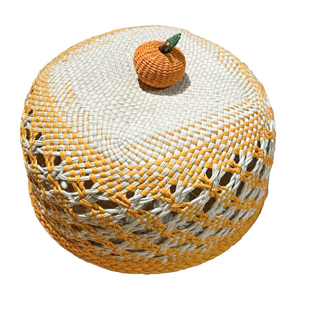 Woven bread basket with a small pumpkin decoration on a white background