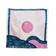 Quilt with pink sun and blue wave design on a white background