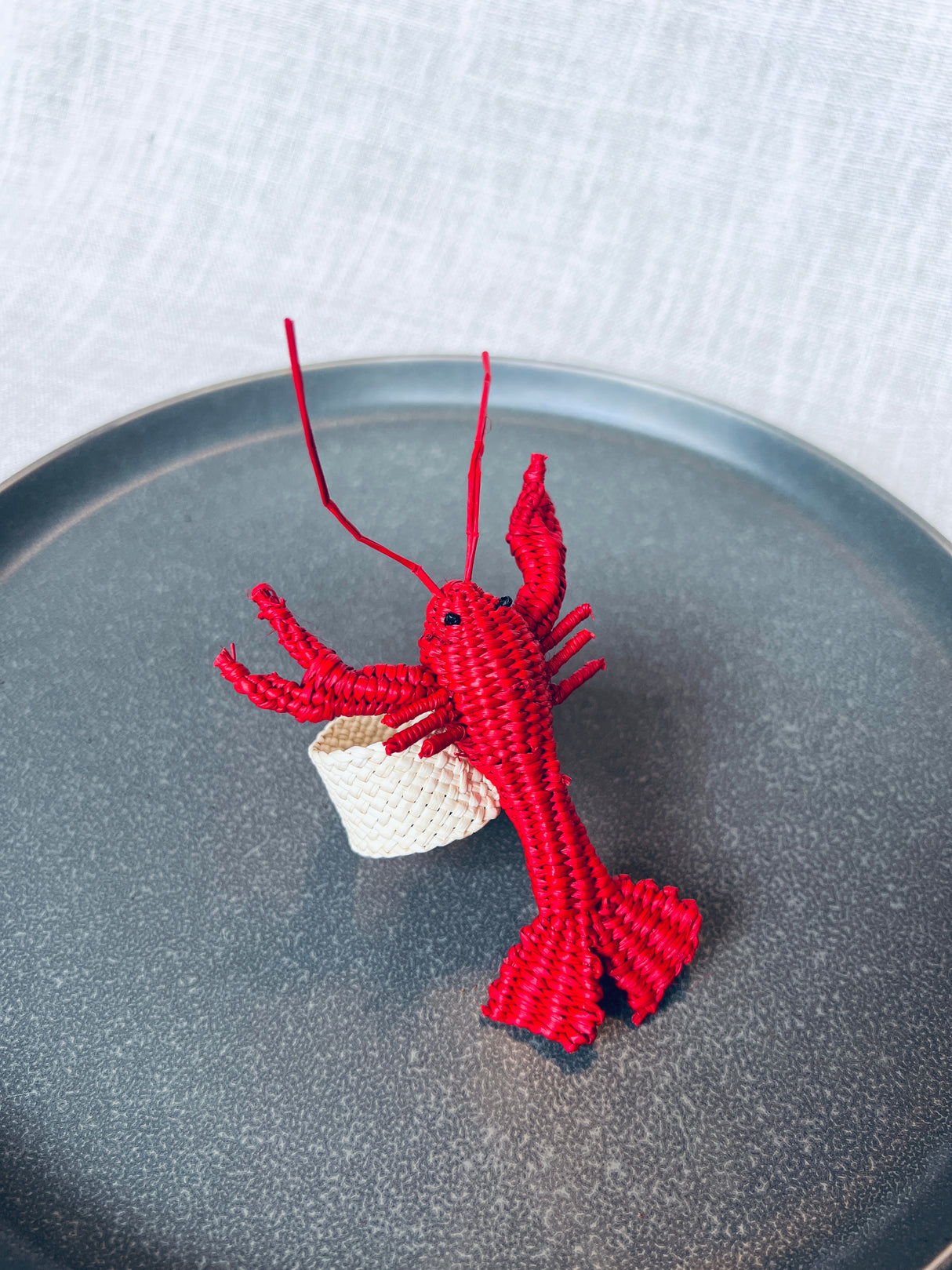 Red lobster napkin ring on a gray plate with a white background