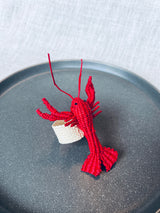 Red lobster napkin ring on a gray plate with a white background
