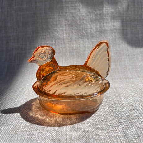 Amber glass hen on a textured gray background