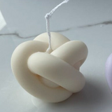 White knot-shaped candle on a white background