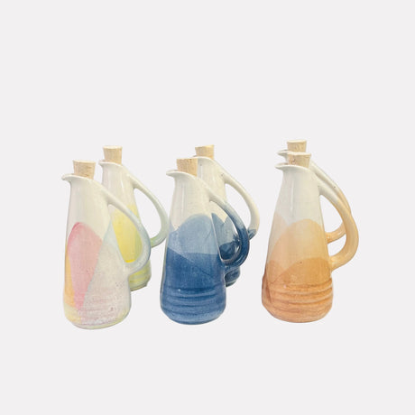 Three ceramic pitchers with handles on a white surface