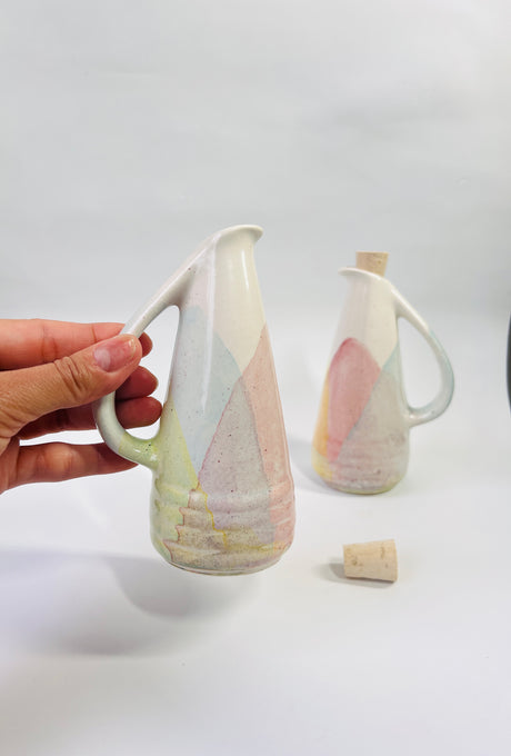 Hand holding a ceramic pitcher with abstract design on a white background