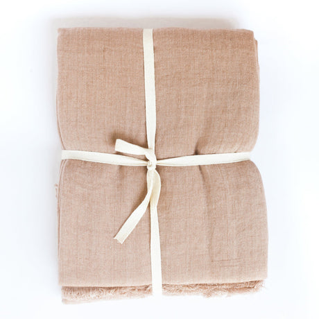 Blush throw blanket tied with a white ribbon on a white background