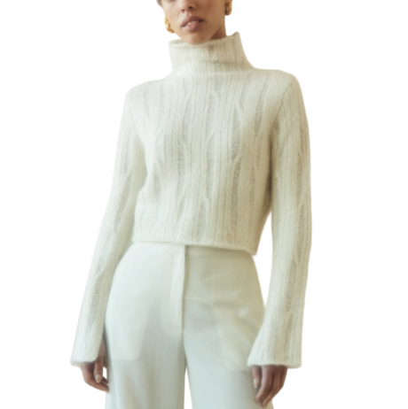 Woman wearing a light green ribbed sweater and pants against a beige background