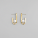 Gold hoop earrings with pearls on a gray background