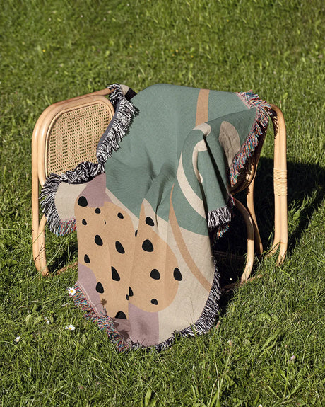 Retro-Futuristic Cotton Woven Throw Blanket in dusty pink, sage green, and cream with fringe edges.