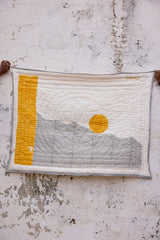 Textile art piece with a yellow square and circular design on a textured surface