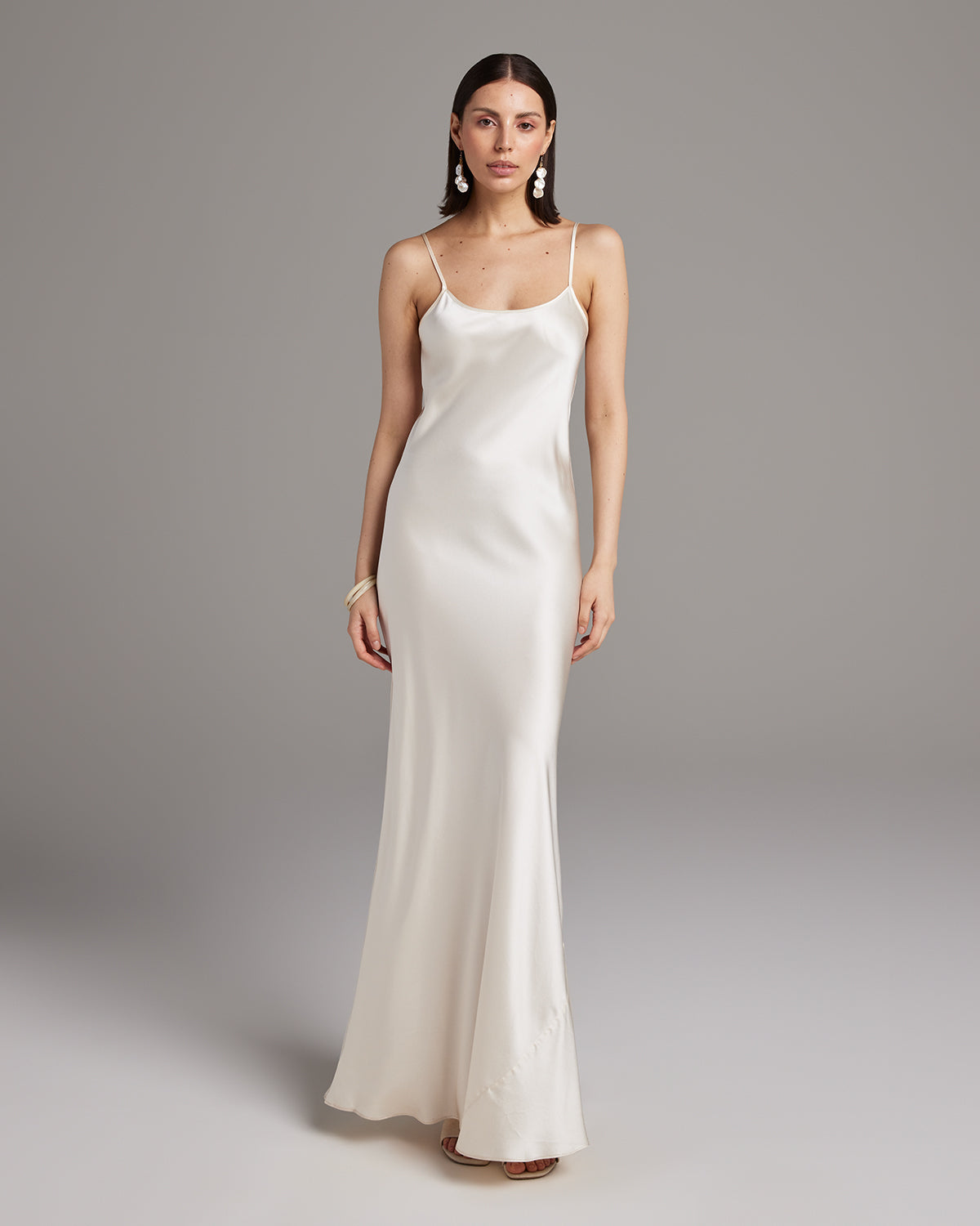 Woman wearing a white satin slip dress against a gray background