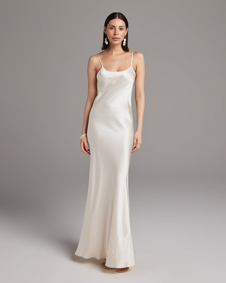Woman wearing a white satin slip dress against a gray background