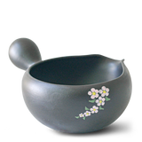 The Black Flowers Ceramic Matcha Bowl features a spout and showcases a pink and white floral design. Ideal for Japanese tea ceremonies, it complements the traditional bamboo whisk included in the Organic Japanese Matcha Set.