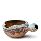 Ceramic pipe with a round bowl and handle, glazed in earthy speckled green and brown tones, reminiscent of the Brown Ceramic Matcha Bowl from the Organic Japanese Matcha Set.