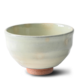 The Kohiki White Clay Matcha Bowl with a textured base, part of a set including a bamboo whisk, whisk holder, and organic Japanese matcha, is displayed against a white background.