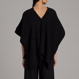 Black poncho worn by a person on a gray background