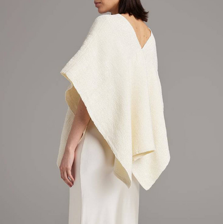 Woman wearing a white textured shawl over a plain background