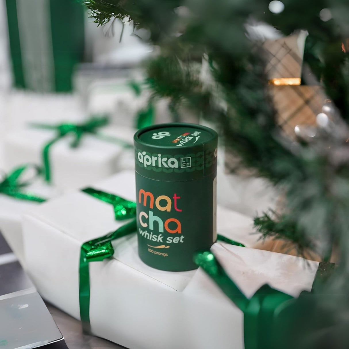A Matcha Bamboo Whisk Set elegantly adorns wrapped gifts with green ribbons beneath the Christmas tree, promising a delightful matcha experience.