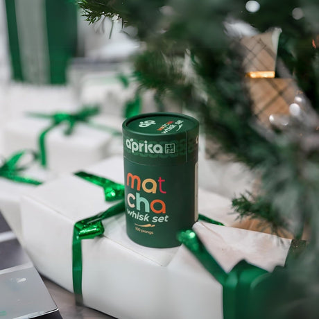 A Matcha Bamboo Whisk Set elegantly adorns wrapped gifts with green ribbons beneath the Christmas tree, promising a delightful matcha experience.