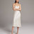 Woman wearing a white satin slip dress against a plain background
