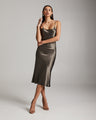 Woman wearing a metallic slip dress against a plain background