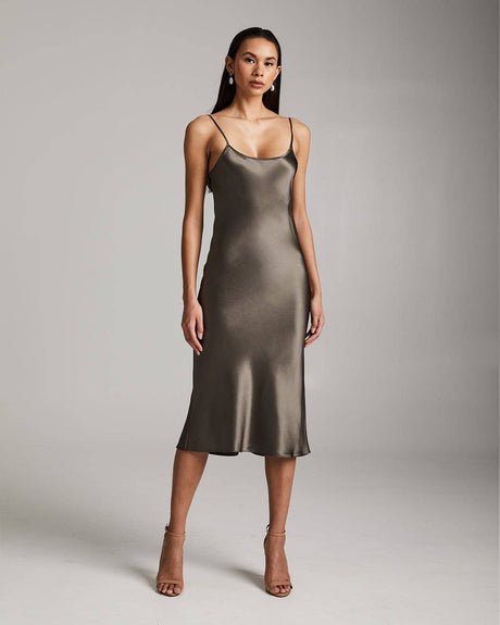 Woman wearing a metallic slip dress against a plain background