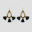 Pair of gold beaded earrings with black tassels on a light gray background