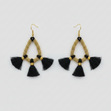 Pair of gold beaded earrings with black tassels on a light gray background