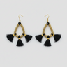 Pair of gold beaded earrings with black tassels on a light gray background