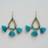 Pair of turquoise tassel earrings with gold accents on a light gray background