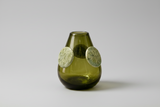 Green glass vase with circular decorations on a white background