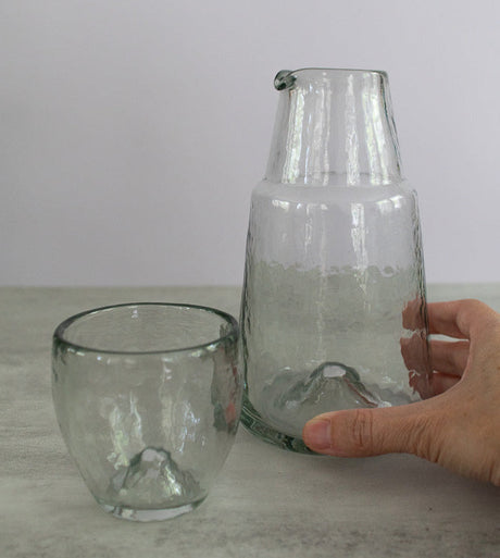 Clear glass pitcher and cup on a light surface with a neutral background