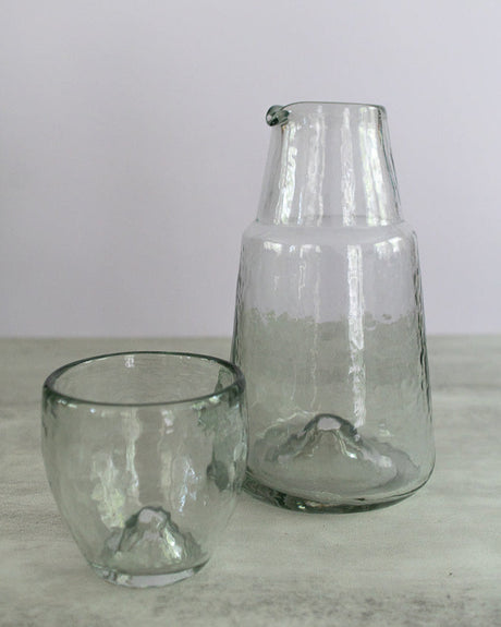Two clear glass vessels on a light surface with a plain background