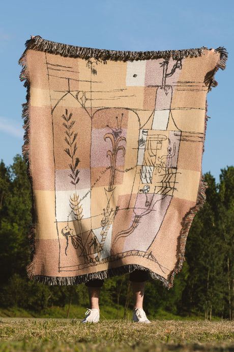 Abstract woven throw blanket in warm yellow, orange, and beige tones with artistic linework.
